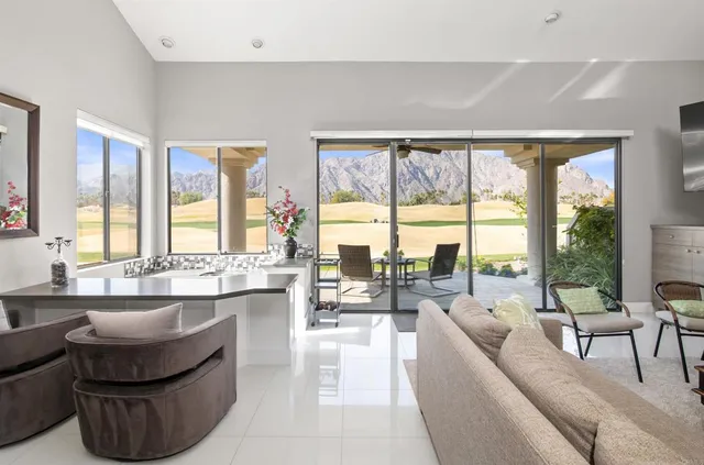 a living room with couches large windows and a dining table with large window