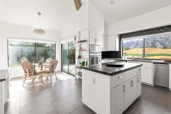 a kitchen with stainless steel appliances granite countertop a table chairs and a view of living room