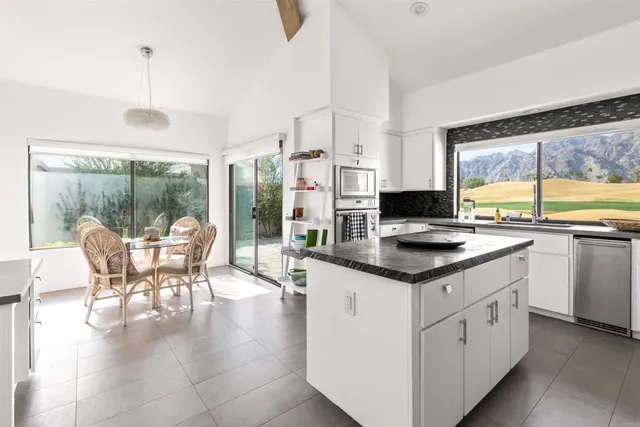 a kitchen with stainless steel appliances granite countertop a table chairs and a view of living room