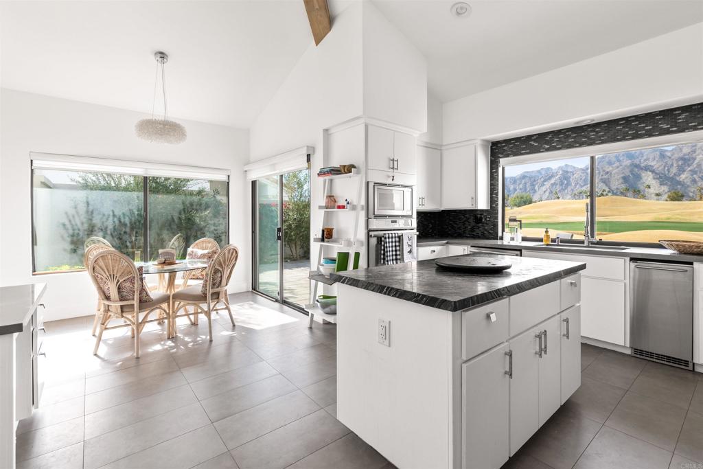 54877 Inverness Way La Quinta, CA 92253 - Photo 20 of 60 a kitchen with stainless steel appliances granite countertop a table chairs and a view of living room