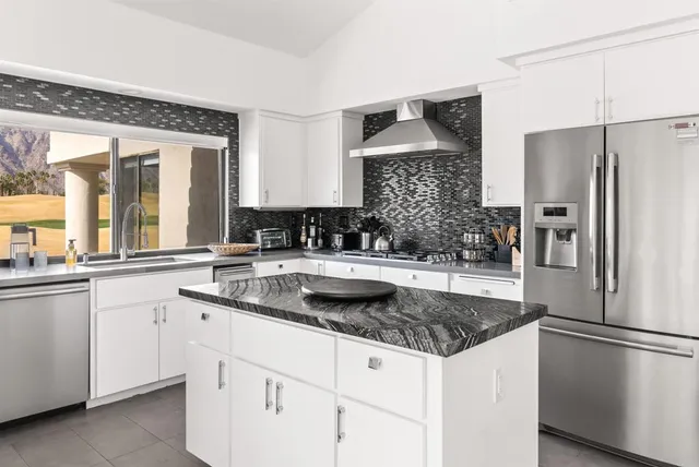 a kitchen with granite countertop a sink stove and refrigerator