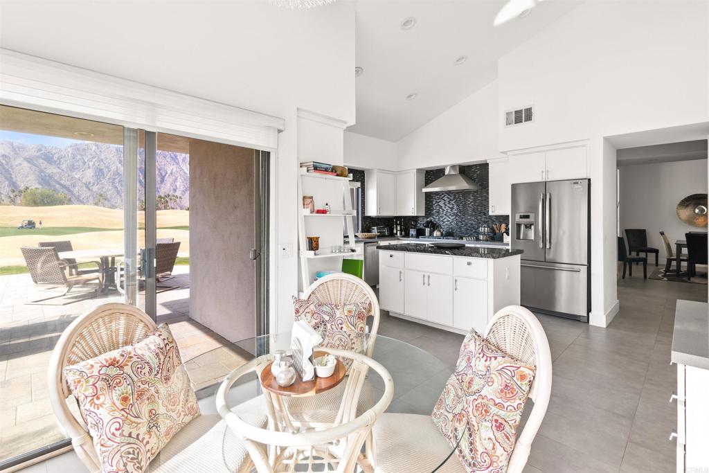 54877 Inverness Way La Quinta, CA 92253 - Photo 24 of 60 a kitchen with stainless steel appliances granite countertop a stove a kitchen island a dining table and chairs