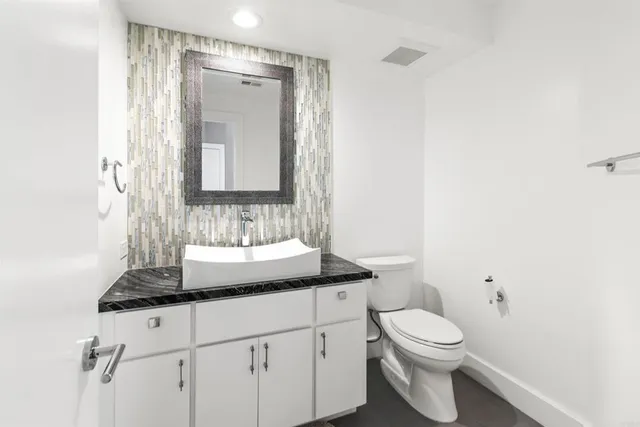 a bathroom with a granite countertop sink toilet a mirror and shower