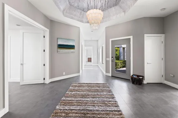 a view of a hallway with wooden floor and a chandelier