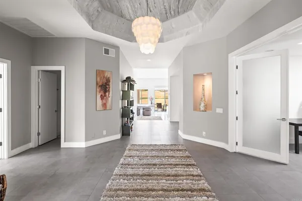 a view of a hallway with wooden floor and a chandelier