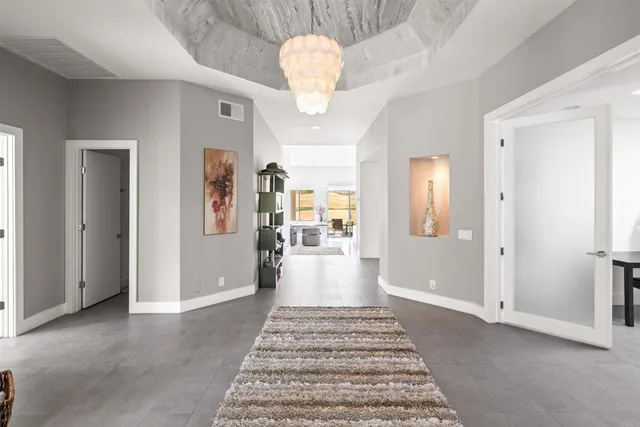 a view of a hallway with wooden floor and a chandelier