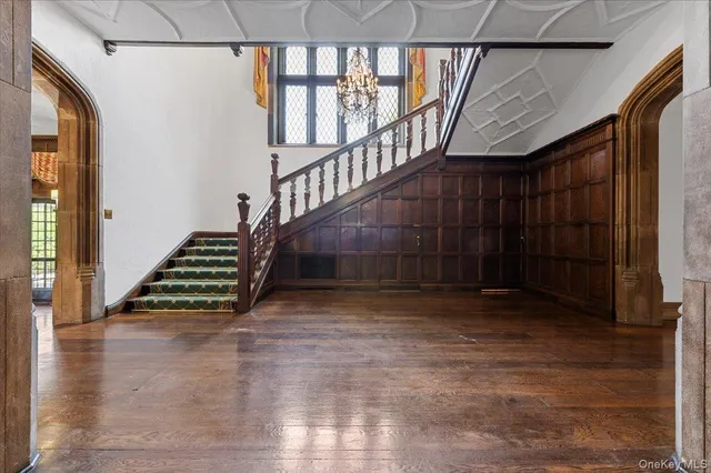 a view of an empty room with wooden floor and a fireplace