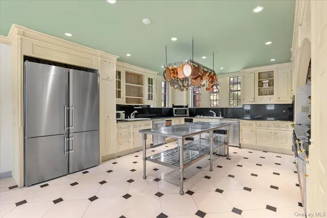 a kitchen with stainless steel appliances a sink a stove a dining table and chairs