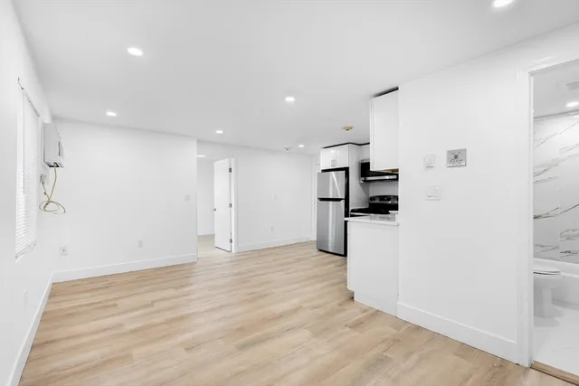 a view of kitchen with refrigerator and white cabinets