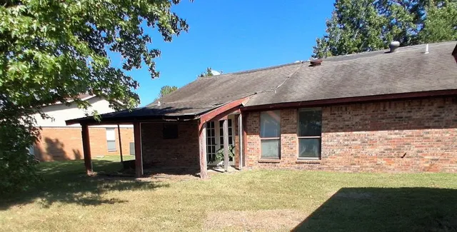 a backyard of a house with large trees and a covered with wooden fence