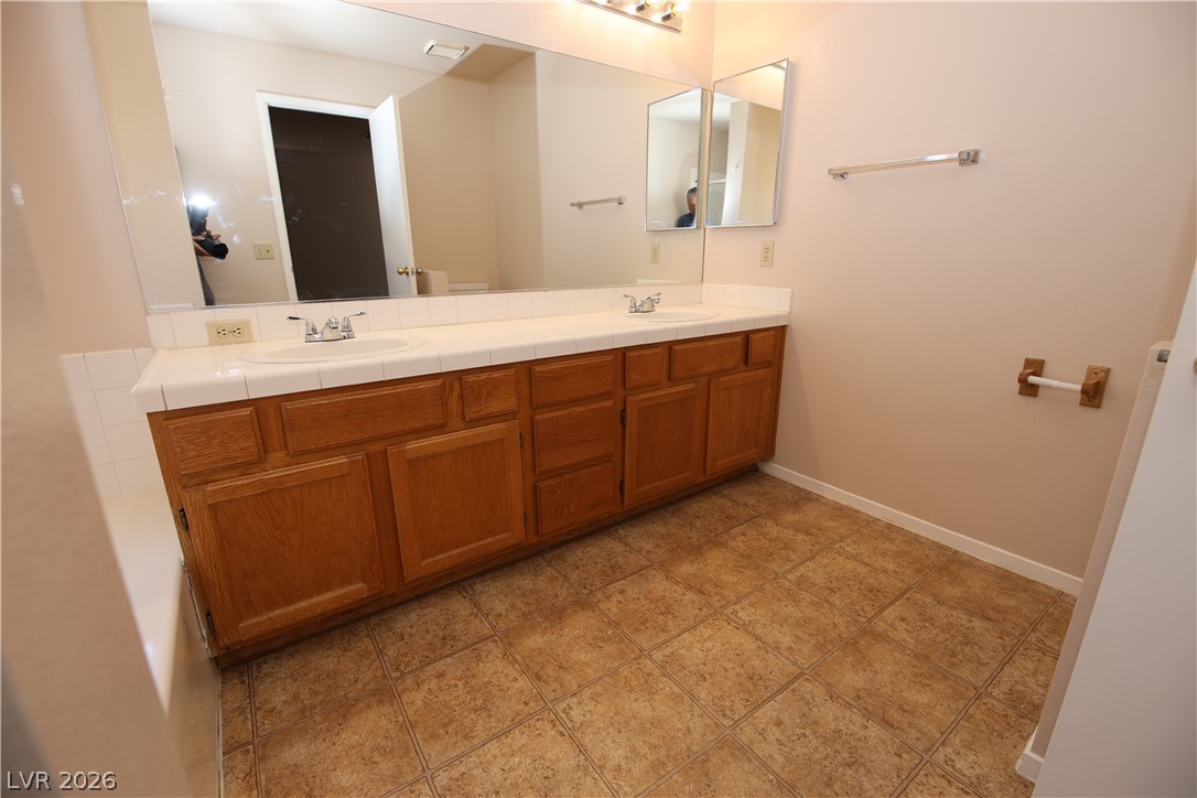 8220 Maplestar Road Las Vegas, NV 89128 - Photo 18 of 29 Double vanity sinks and ample cabinet storage enhance this functional primary bathroom space.