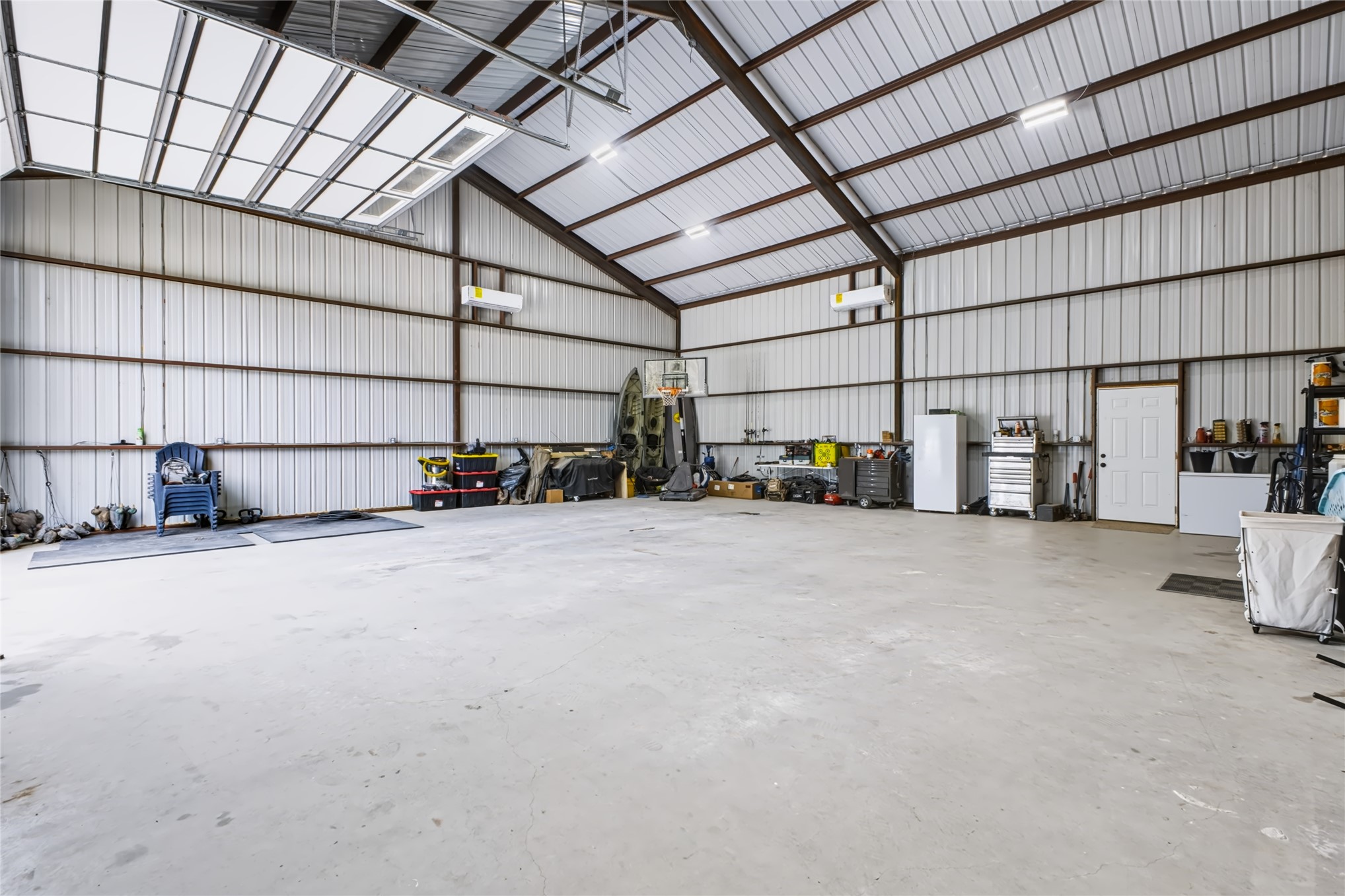 3607 South Half Bank Road Atoka, OK 74525 - Photo 38 of 82 Expansive interior space featuring a high-pitched metal ceiling, concrete flooring, and an overhead door