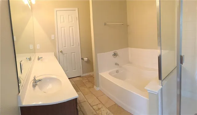 a bathroom with a tub sink and mirror