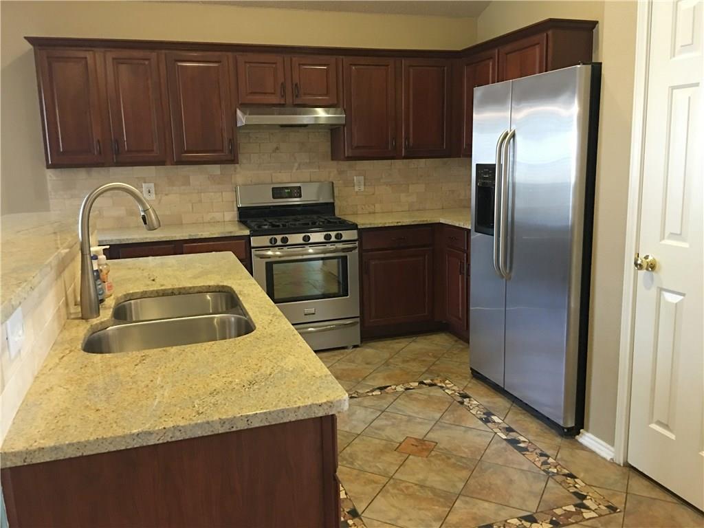 6740 Red Rock Trail Watauga, TX 76137 - Photo 4 of 16 a kitchen with stainless steel appliances granite countertop a stove a refrigerator and a sink
