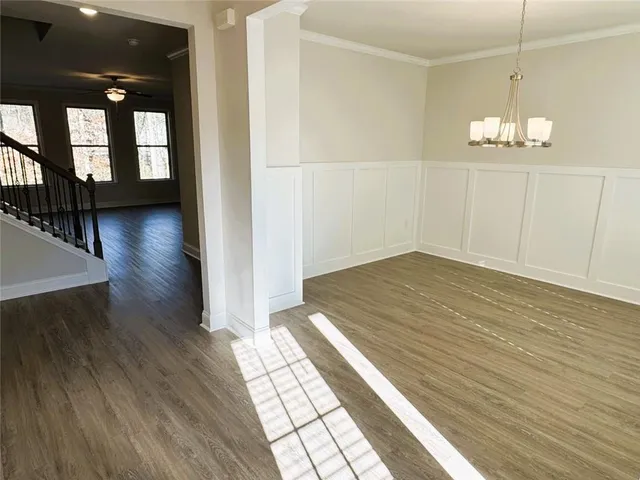 a view of a room with wooden floor staircase and a kitchen space