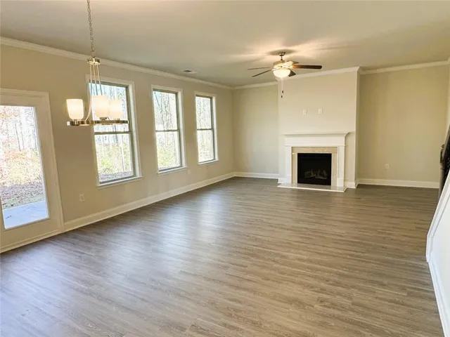 an empty room with wooden floor fireplace and windows