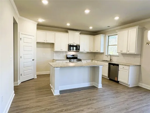 a kitchen with granite countertop white cabinets and stainless steel appliances