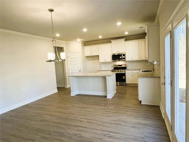 a kitchen with kitchen island a sink a stove a refrigerator and white cabinets