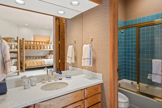 a bathroom with a granite countertop sink a toilet a mirror and shower