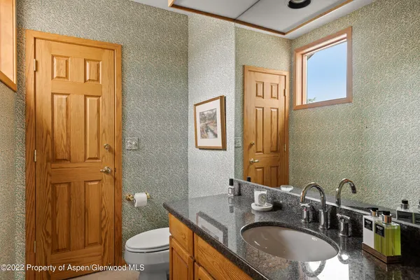 a bathroom with a granite countertop sink toilet and a mirror