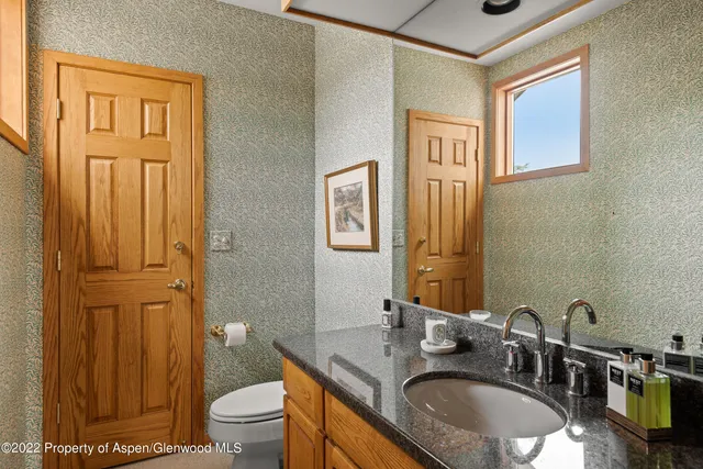 a bathroom with a granite countertop sink toilet and a mirror