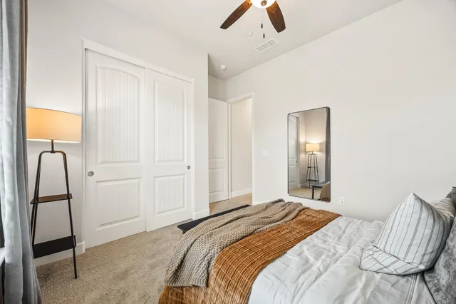 a bedroom with a bed a mirror on dresser and next to a window