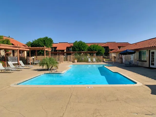 a view of swimming pool with outdoor seating and house in the background