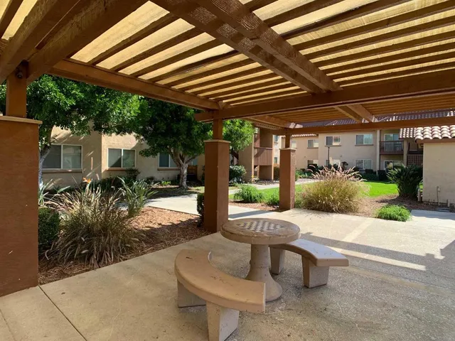 a view of a patio with table and chairs potted plants and floor to ceiling window