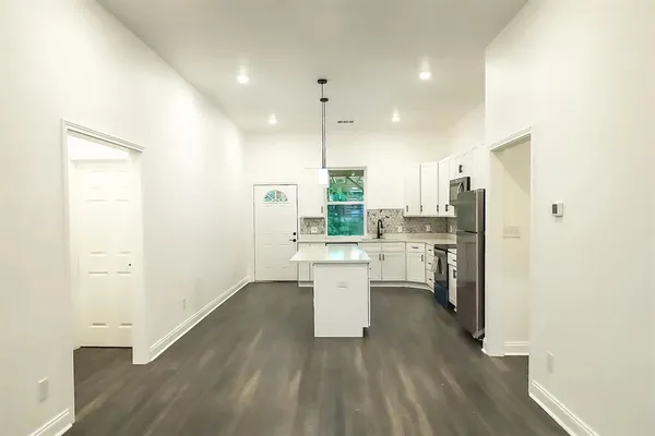 a kitchen with a refrigerator and white cabinets