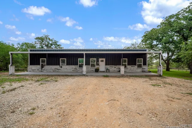 a front view of house with yard and trees in the background