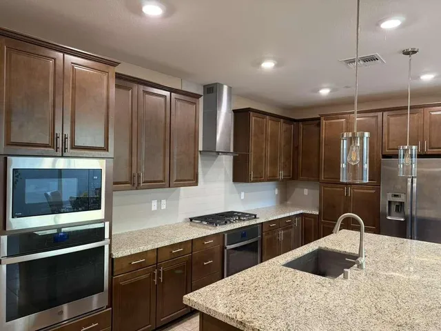 a kitchen with stainless steel appliances granite countertop a stove a sink and a refrigerator