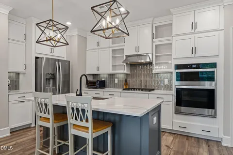 a kitchen with stainless steel appliances kitchen island granite countertop a table chairs in it and white cabinets