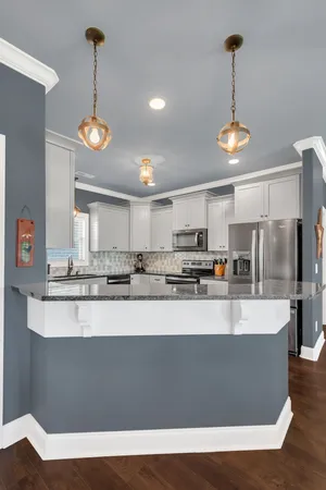 a large kitchen with kitchen island stainless steel appliances a stove and a chandelier