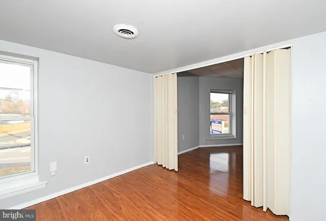 a view of an empty room with window and wooden floor