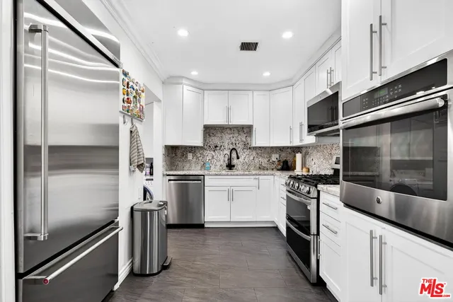 a kitchen with stainless steel appliances granite countertop a refrigerator and a stove