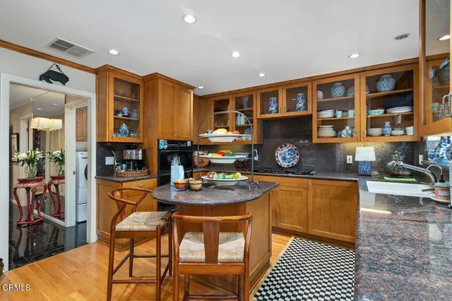 a kitchen with stainless steel appliances granite countertop a stove a refrigerator a sink a dining table and chairs with wooden floor