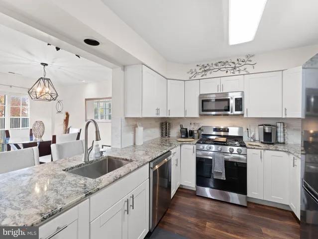 a kitchen with granite countertop a sink stainless steel appliances and white cabinets