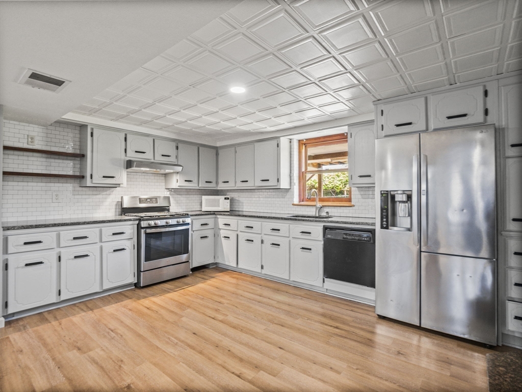146 Lisbon Street Fall River, MA 02721 - Photo 19 of 42 a kitchen with granite countertop stainless steel appliances a refrigerator cabinets and wooden floor