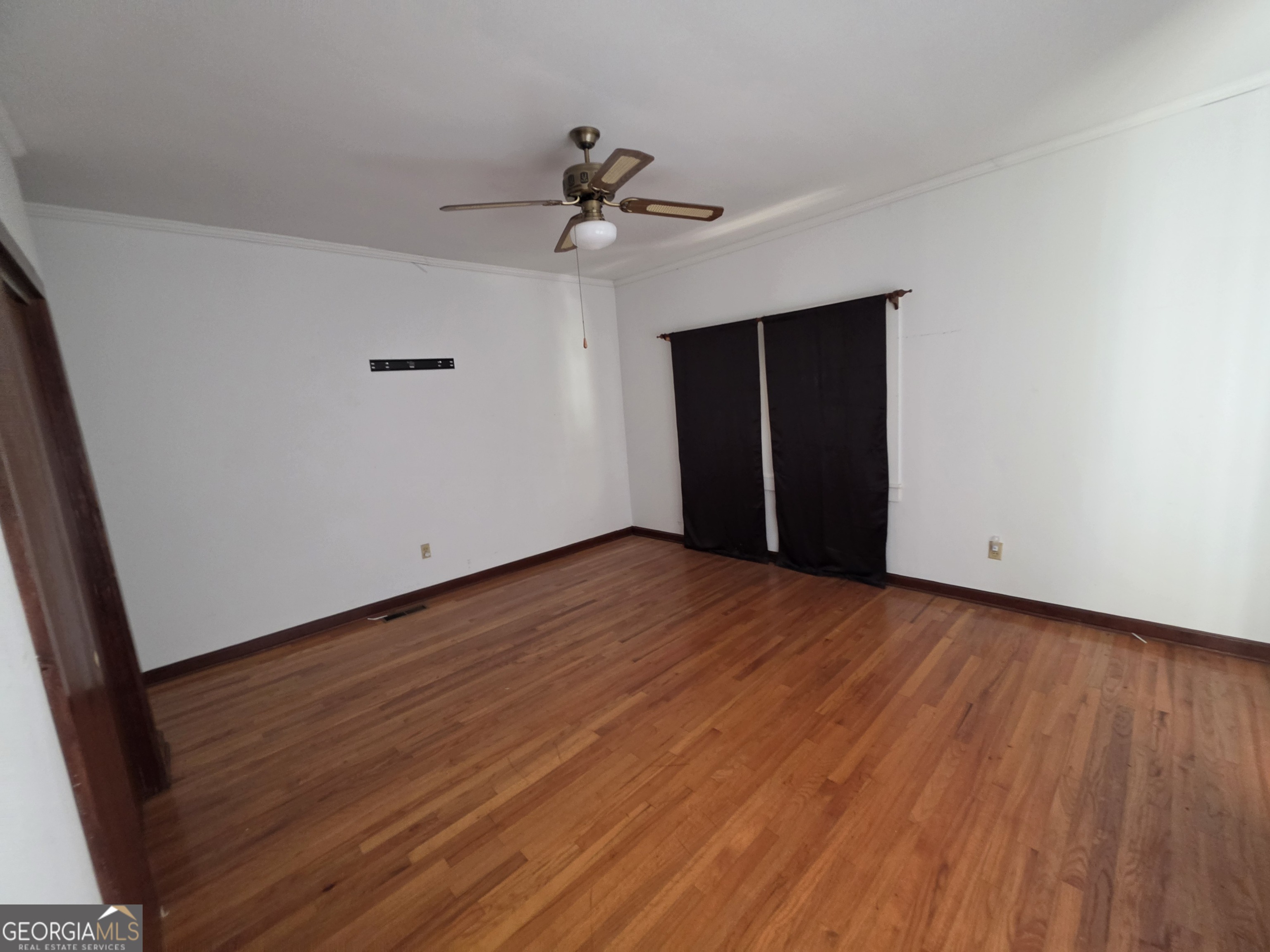 109 Springdale Drive Washington, GA 30673 - Photo 19 of 35 a view of an empty room with wooden floor and a ceiling fan