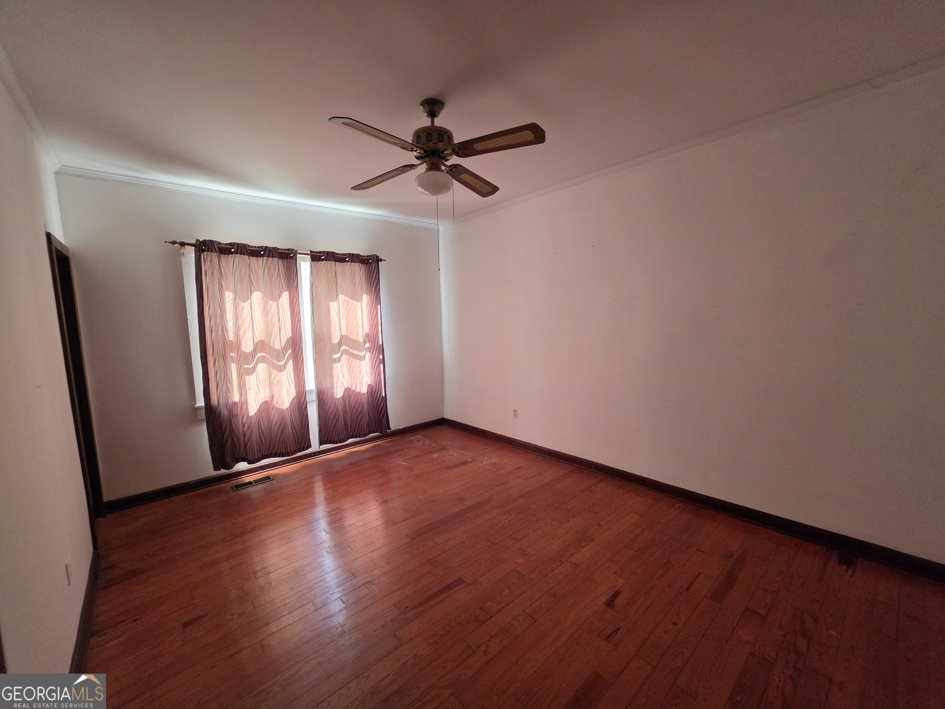 109 Springdale Drive Washington, GA 30673 - Photo 22 of 35 an empty room with wooden floor fan and windows
