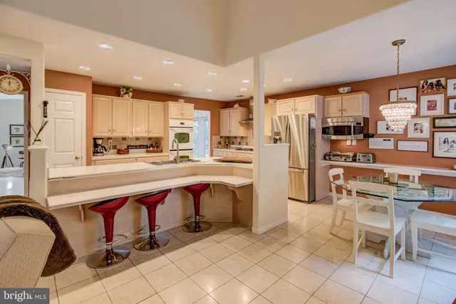 a kitchen with stainless steel appliances kitchen island granite countertop a table chairs microwave and sink