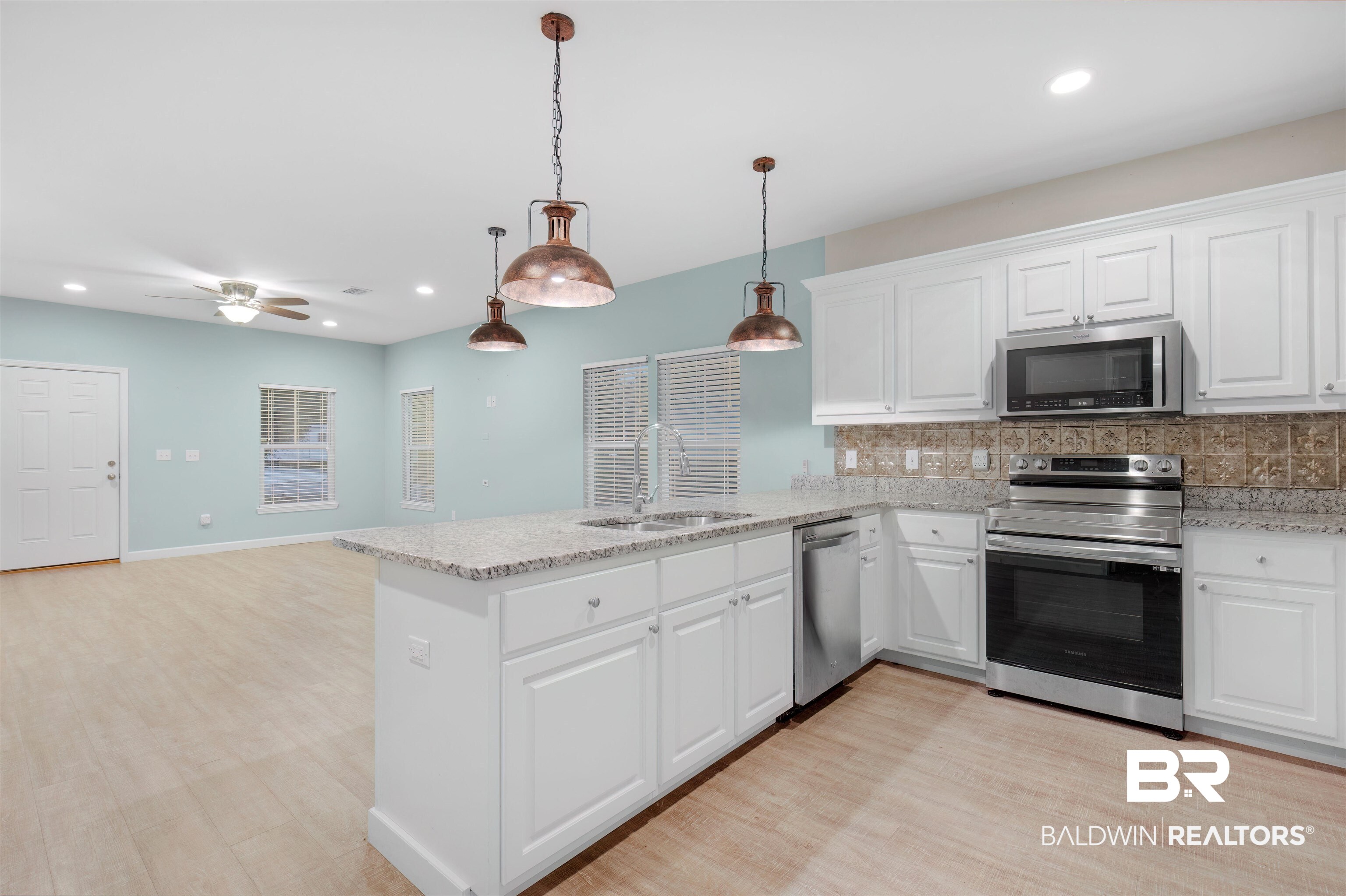 5625 Georgia Street Orange Beach, AL 36561 - Photo 13 of 30 Kitchen with stainless steel appliances, white cabinets, decorative backsplash, and sink