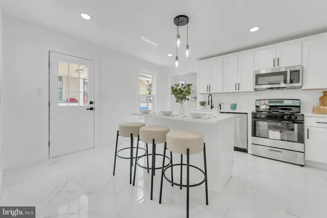 a kitchen with stainless steel appliances kitchen island granite countertop a stove a sink a refrigerator and white cabinets with wooden floor