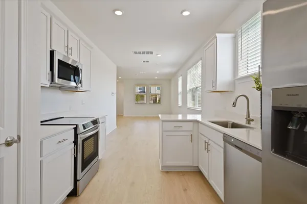 a kitchen with stainless steel appliances granite countertop grey cabinets a stove top oven a sink and dishwasher