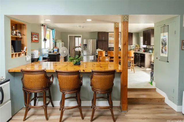 a dining hall with stainless steel appliances kitchen island a table and chairs
