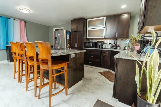 a kitchen with stainless steel appliances kitchen island granite countertop a table chairs and a refrigerator