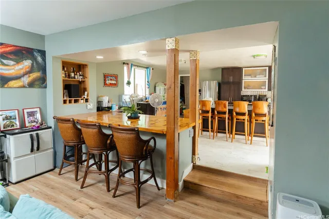 a dining hall with stainless steel appliances kitchen island granite countertop a dining table and chairs with wooden floor