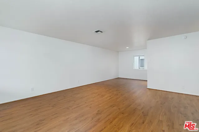 a view of an empty room with wooden floor and a chandeliers
