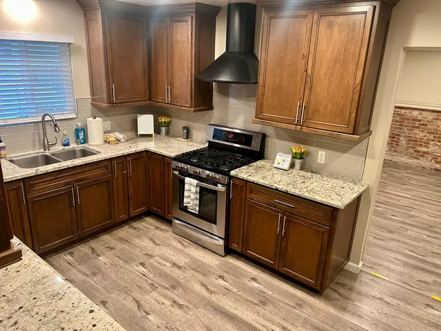 a kitchen with stainless steel appliances granite countertop a sink stove and cabinets