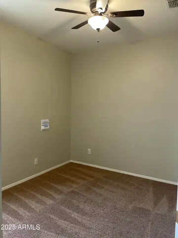 an empty room with a chandelier fan and windows